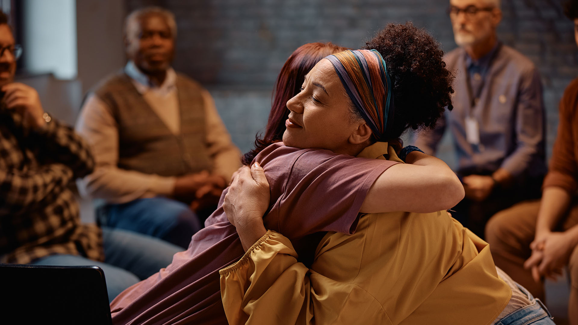 Peer support group participants sharing encouragement and connection during a mental health recovery program.